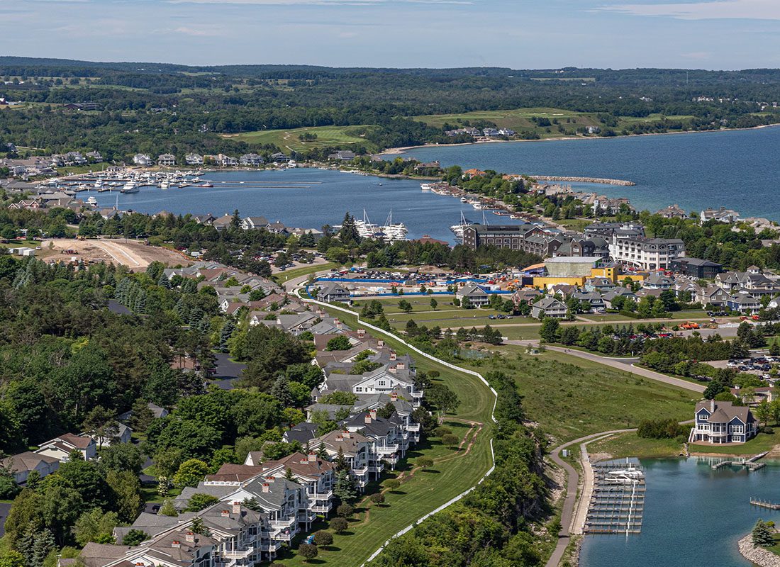 Fremont, MI - Aerial View of Bay Harbor, Michigan Displaying Lake Michigan and Many Trees Around Town